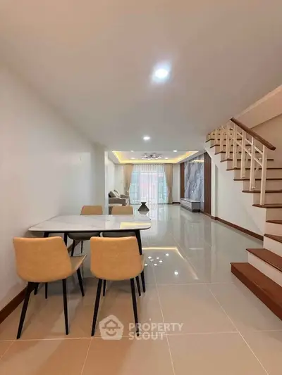 Spacious modern living room with elegant staircase and dining area