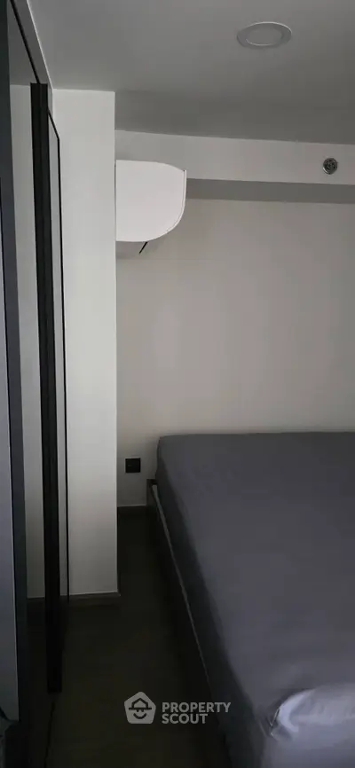 Modern minimalist bedroom with sleek design and air conditioning unit.