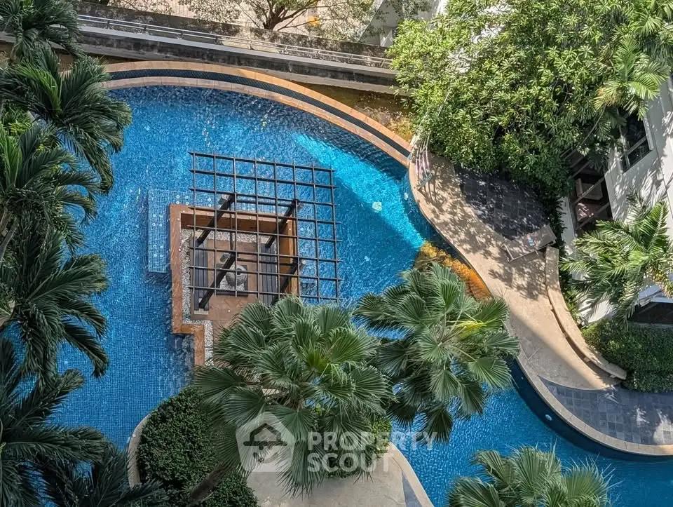 Luxurious aerial view of a tropical swimming pool surrounded by lush greenery in a modern residential complex.