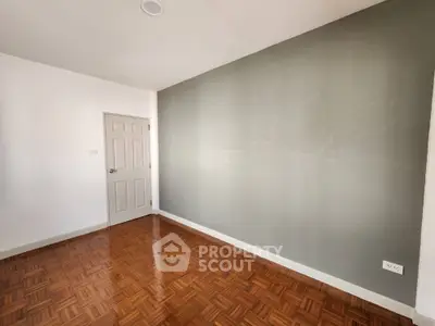 Spacious empty room with parquet flooring and neutral walls, perfect for customization.