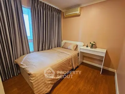 Cozy bedroom with single bed, elegant curtains, and wooden flooring in a modern apartment.