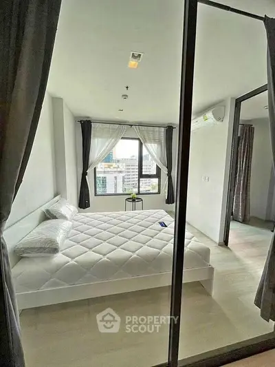 Modern bedroom with city view, featuring large windows and minimalist decor.