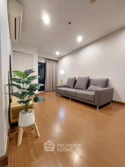Modern living room with sleek wooden flooring and stylish gray sofa