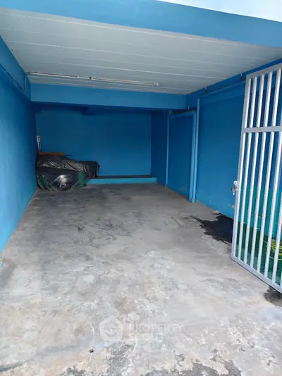 Spacious blue-painted garage with secure metal gate and ample storage space.