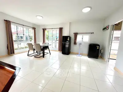 Spacious living room with large windows and modern dining area, perfect for family gatherings.