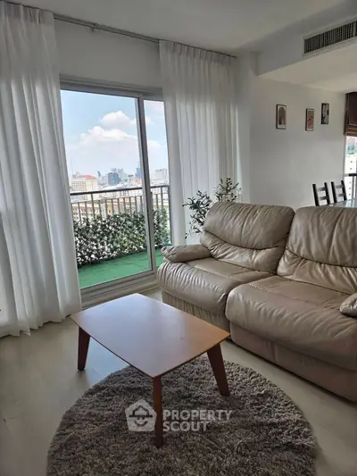 Stylish living room with leather sofa and city view balcony, perfect for urban living.