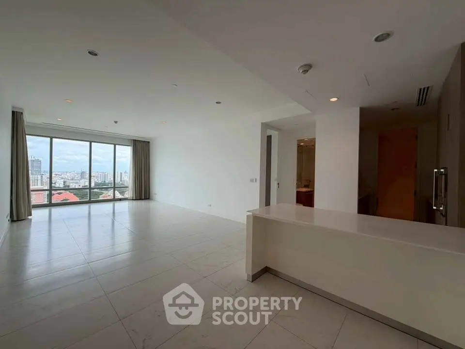 Spacious modern living room with large windows offering stunning city views in a high-rise apartment.