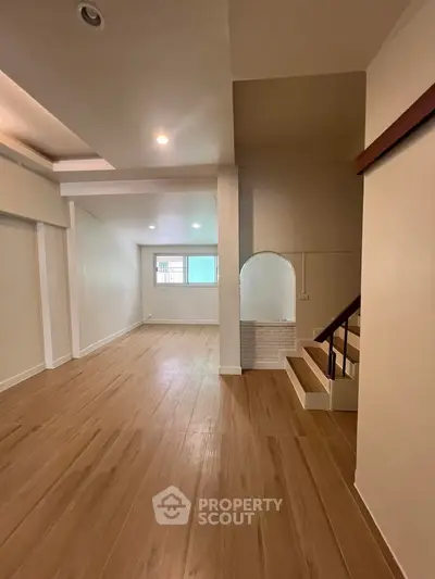 Spacious open-plan living area with wooden flooring and staircase, perfect for modern living.