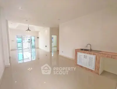 Spacious open-plan living area with modern kitchenette and large windows leading to balcony.