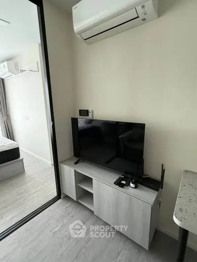Modern living room with sleek TV setup and air conditioning in a stylish apartment.