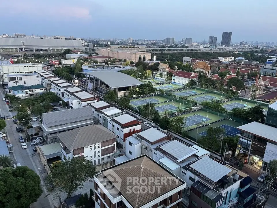 Aerial view of urban residential area with tennis courts and city skyline.