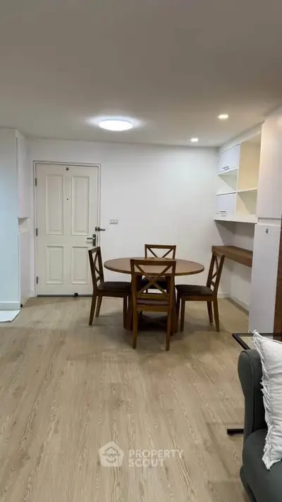 Modern dining area with wooden table and chairs in a cozy apartment setting.