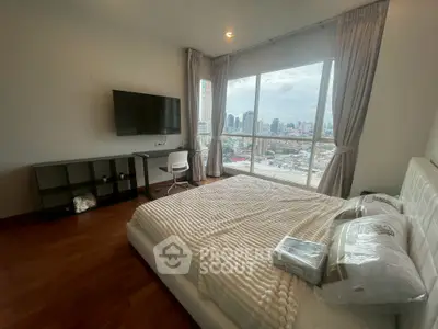 Spacious bedroom with city view, modern furnishings, and large windows for natural light.