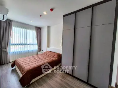 Modern bedroom with large window and sleek wardrobe in a stylish apartment.