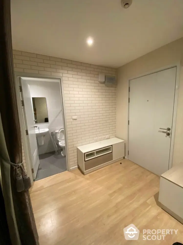 Modern apartment entrance with wooden flooring and adjacent bathroom