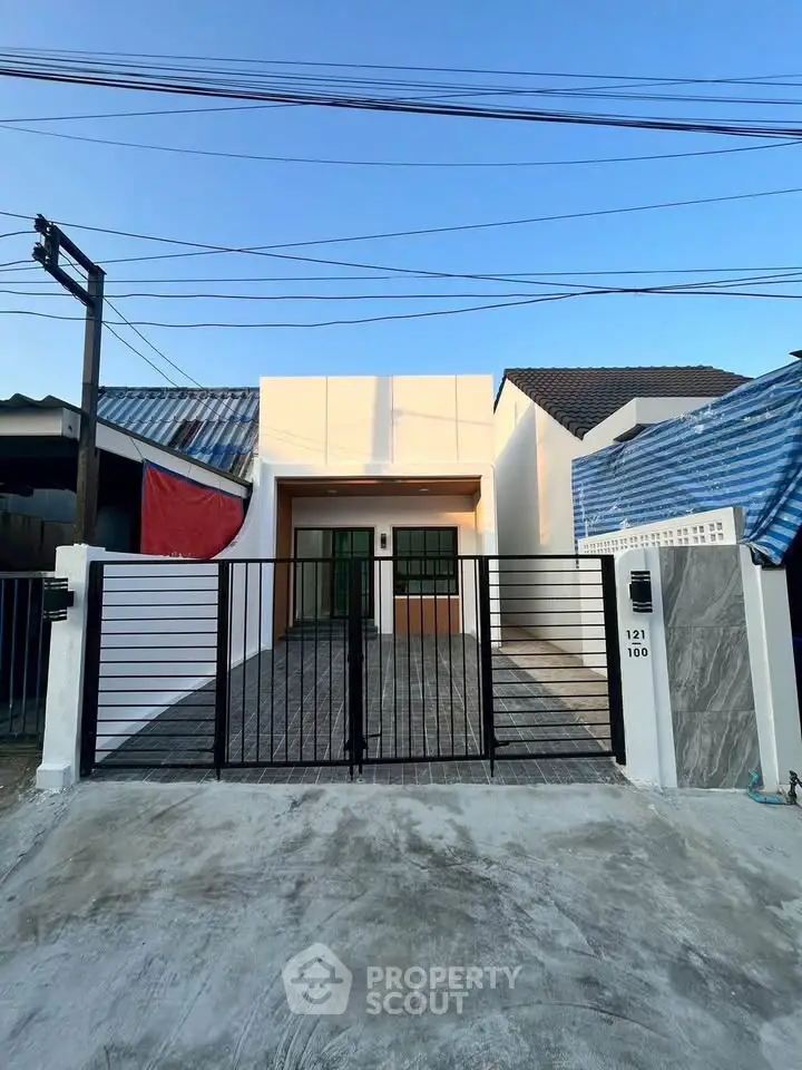 Modern single-story house with gated entrance and sleek design in a suburban neighborhood.