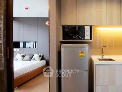 Modern apartment interior with kitchen and bedroom view, featuring sleek cabinetry and contemporary design.