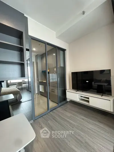 Modern living room with sleek design and glass partition leading to bedroom