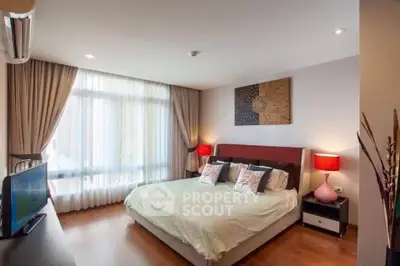 Spacious bedroom with modern decor and large window for natural light.
