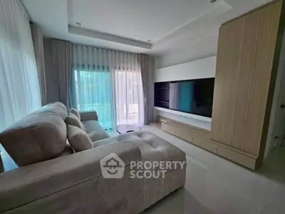 Modern living room with plush sofa and large TV, featuring elegant curtains and sleek cabinetry.