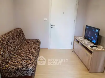Cozy living room with patterned sofa and flat-screen TV, perfect for relaxation.