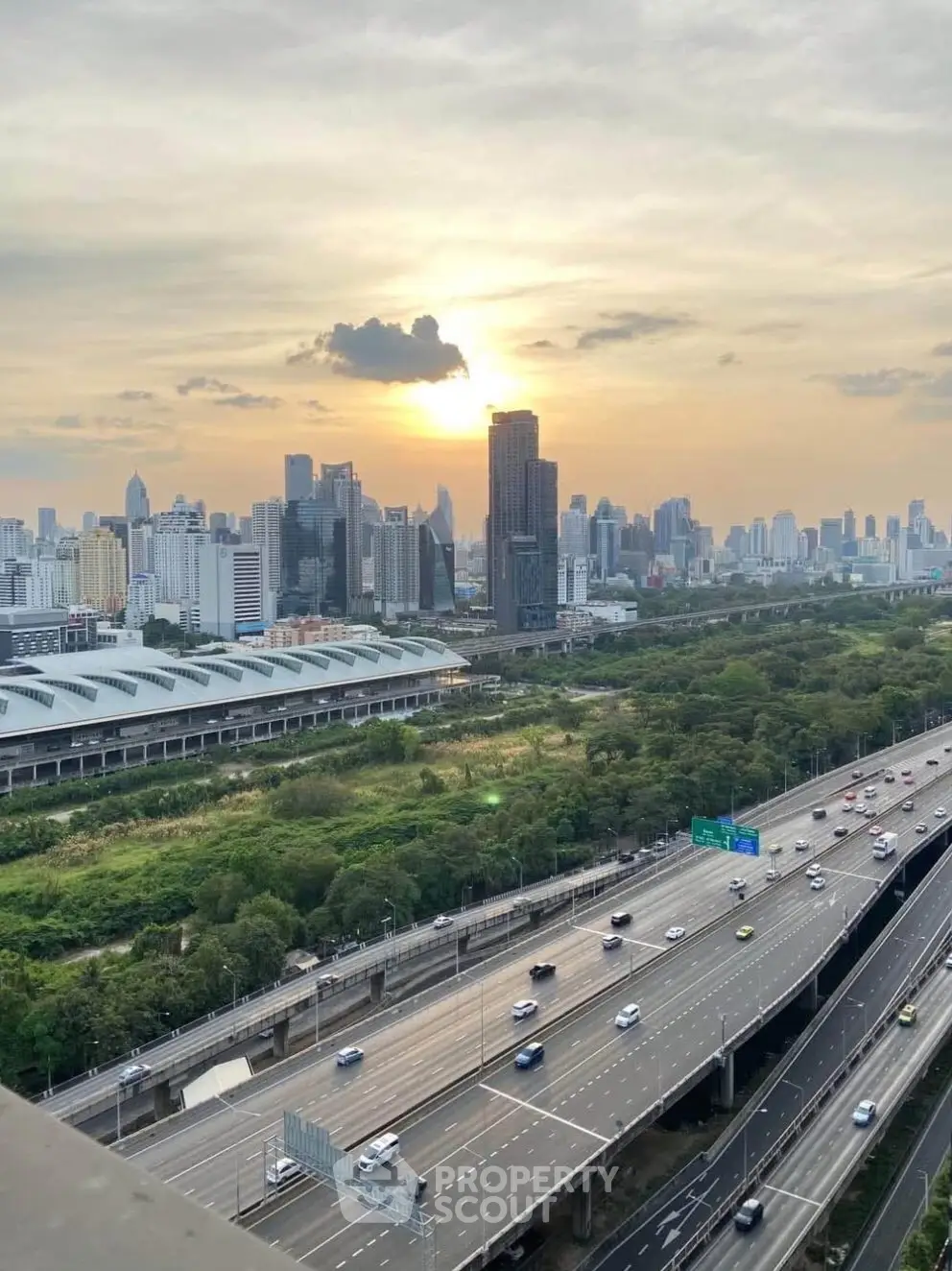 Stunning cityscape view with lush greenery and modern skyline at sunset.