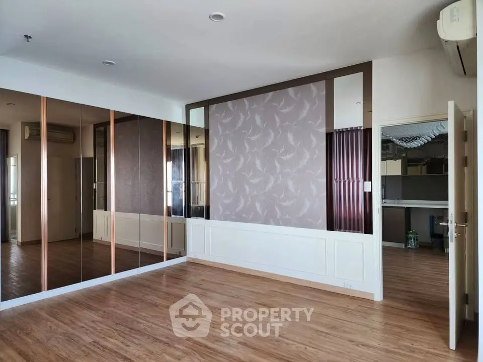 Spacious empty living room with wooden flooring and mirrored wall, perfect for customization.