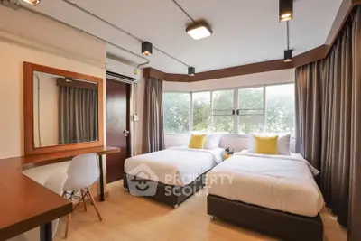 Modern bedroom with twin beds and large windows offering natural light.