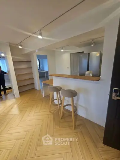 Modern open-plan living area with stylish bar stools and wooden flooring