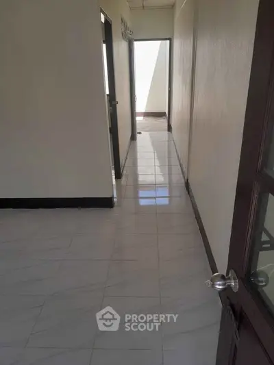 Spacious hallway with glossy tiled flooring leading to multiple rooms in a modern apartment.