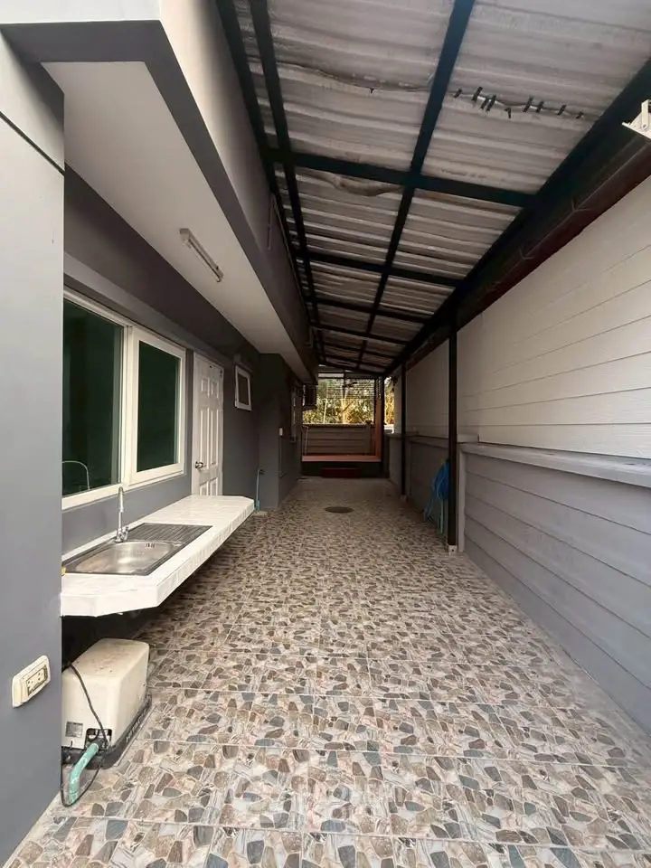 Spacious covered outdoor area with tiled flooring and modern sink, perfect for versatile use.