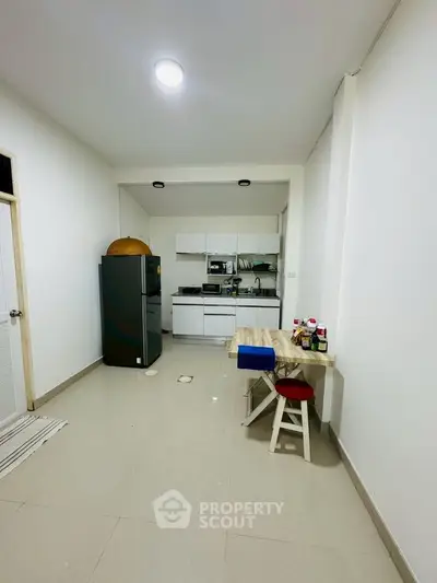 Modern kitchen with sleek appliances and minimalist dining area in a cozy apartment.