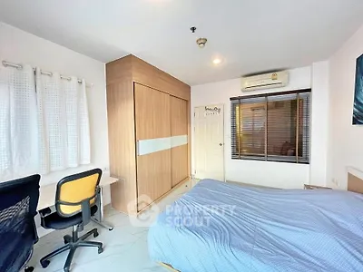Spacious bedroom with modern furnishings and ample natural light, featuring a built-in wardrobe and air conditioning.