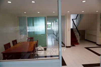 Spacious dining area with wooden table and modern staircase in bright interior