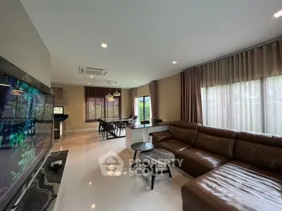 Spacious modern living room with leather sofa and large windows offering natural light.