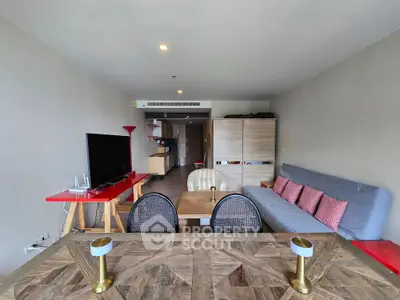 Spacious living room with modern decor and open layout, featuring a cozy sofa and large TV.