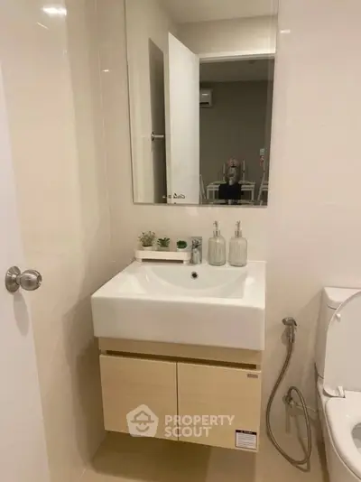 Modern bathroom with sleek sink and mirror, featuring minimalistic design and neutral tones.