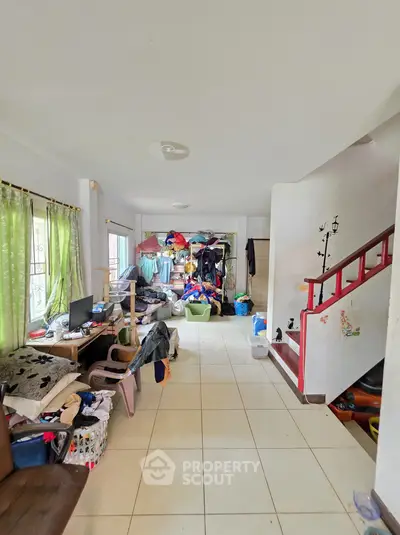 Spacious living room with tiled flooring and staircase, ideal for customization and personal touch.