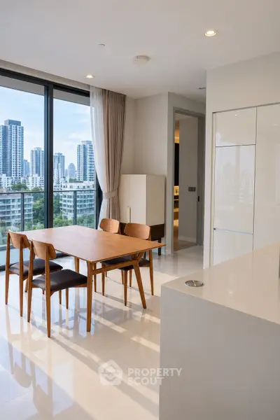 Modern dining area with city view, featuring sleek furniture and large windows in a high-rise apartment.