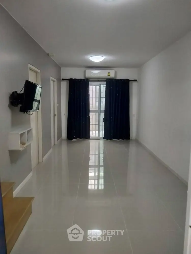 Spacious modern living room with glossy tiled floors and wall-mounted TV.