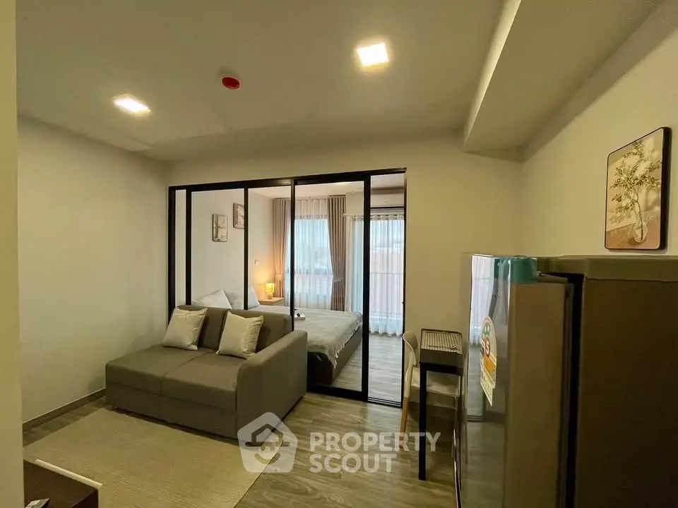 Modern studio apartment with cozy living area and bedroom separated by glass partition.