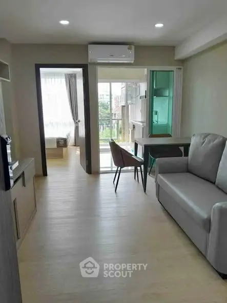 Modern apartment interior with open layout, featuring a cozy living area and a view of the bedroom.