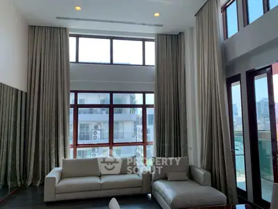 Spacious living room with high ceilings and large windows offering city views.