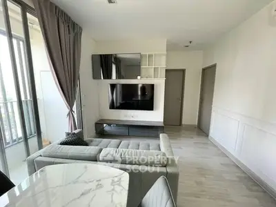 Modern living room with sleek furniture and large TV, featuring elegant decor and natural light.