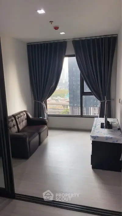 Cozy study room with city view, featuring a leather sofa and elegant curtains.