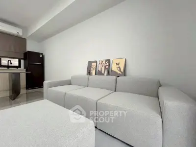 Modern living room with sleek gray sofa and minimalist kitchen design