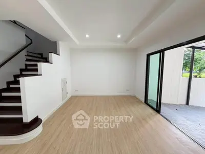 Spacious modern living room with wooden flooring and sliding glass doors to balcony.