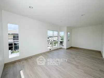 Spacious empty room with large windows and wooden flooring, offering abundant natural light and modern design.