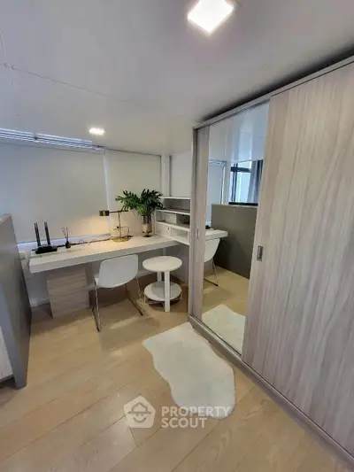 Modern study room with sleek desk, chairs, and mirrored wardrobe in bright apartment.