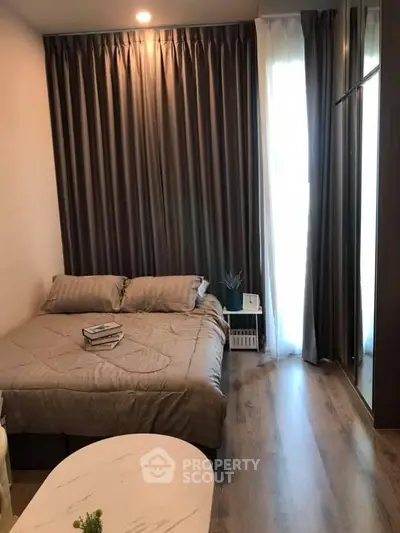 Cozy bedroom with elegant curtains and wooden flooring, perfect for relaxation.